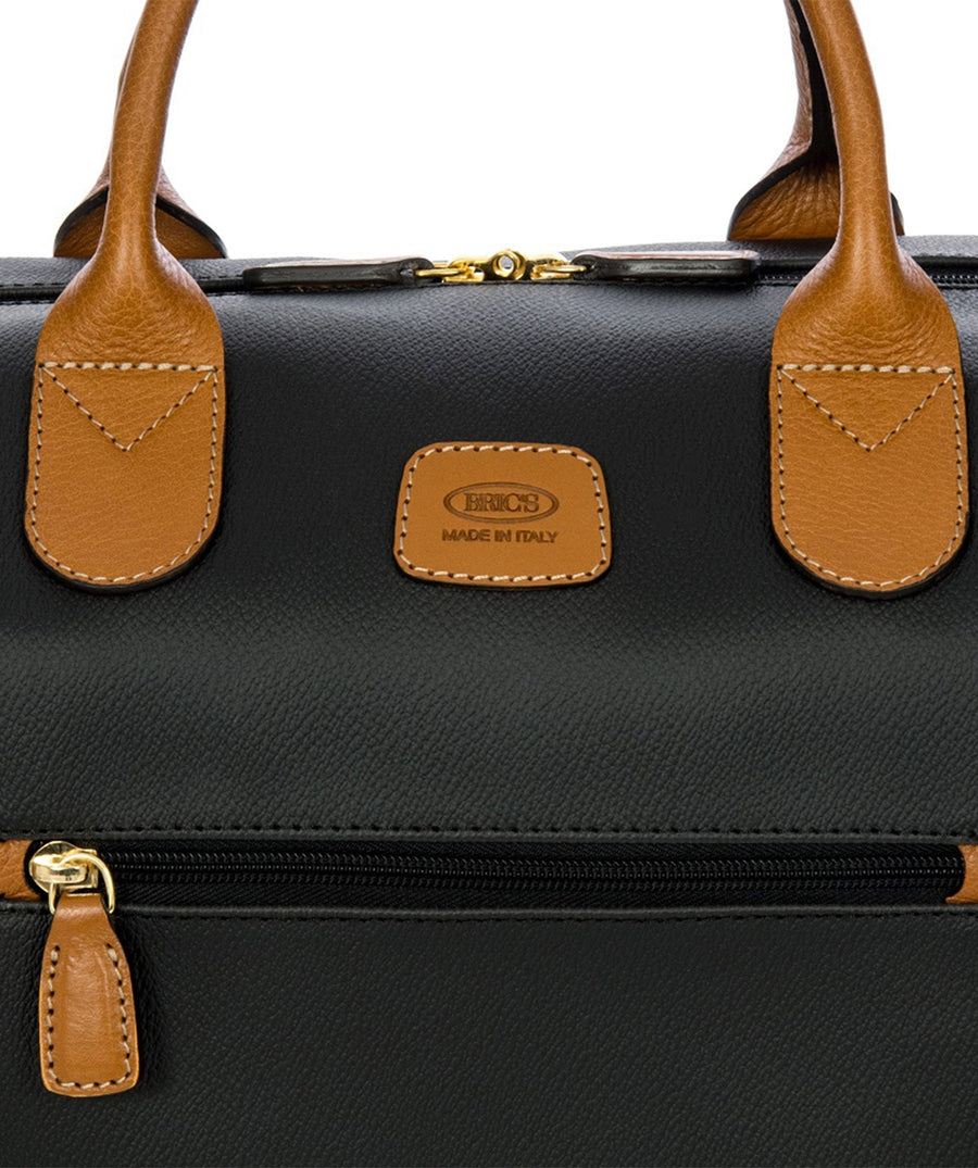 Bric's 18" Firenze Cargo Duffle Bag in black with brown leather accents, featuring double top handles, a front zip pocket, gold-tone zippers, and a spacious interior with logo-printed lining and an inner zip pocket. Style code BBJ20203.